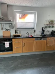 Die moderne Küche hat Holzschränke und eine elegante Arbeitsplatte. Sie ist gut ausgestattet mit Küchengeräten und bietet viel Platz für die Zubereitung von Speisen.