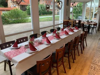 Ein festlich gedeckter Tisch mit roten Partyhüten in einem Restaurant. Der Raum hat große Fenster und eine einladende Atmosphäre.