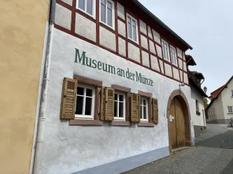 Ein historisches Gebäude mit dem Schriftzug "Museum an der Münze". Die Fassade zeigt traditionelle Fensterladen und ist in sanften Farben gestrichen.