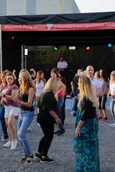 Eine Afterwork-Party im Freien mit vielen tanzenden Menschen. Ein DJ sorgt für die Musik auf der Bühne.