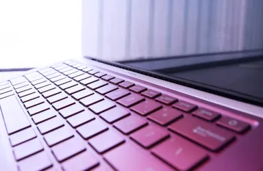 Ein Laptop mit einer modernen Tastatur ist im Bild zu sehen. Die Farben sind in sanften Tönen gehalten und der Fokus liegt auf der Tastatur.