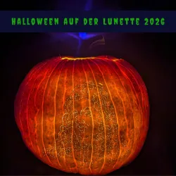 Ein leuchtender Kürbis mit einer künstlerischen Darstellung auf der Oberfläche. Darüber steht "HALLOWEEN AUF DER LUNETTE 2026".