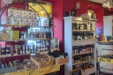 Ein einladendes Geschäft mit Regalen voller öl und Feinkostartikeln. Die Wände sind in einem warmen Rot gestrichen und schaffen eine gemütliche Atmosphäre.