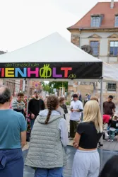 Eine Tanzschule präsentiert ihre Aktivitäten unter einem Zelt auf dem Platz. Menschen versammeln sich, um zuzuschauen und daran teilzunehmen.