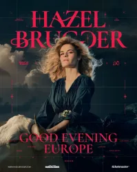 Ein Porträt einer Frau mit blonden Locken, die in einem eleganten schwarzen Kleid posiert. Im Hintergrund steht ein weißes Pferd und der Text „GOOD EVENING EUROPE“ ist sichtbar.