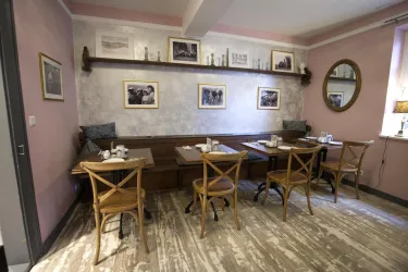 Ein gemütlicher Frühstücksraum mit Holztischen und Stühlen. Der Raum ist in sanften Farbtönen gestaltet und hat Wände mit schönen Bilderrahmen.