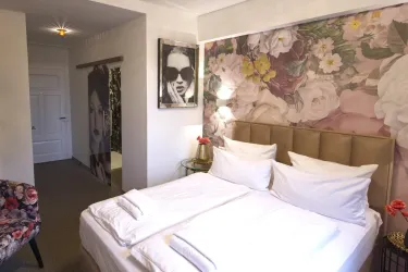 Ein stilvolles Schlafzimmer mit zwei Betten und einer blühenden Wandgestaltung. Der Raum ist modern und elegant mit einem gemütlichen Sessel.