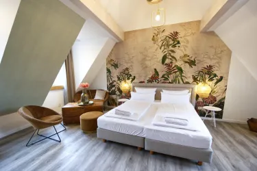 Ein elegantes Zimmer mit einem Doppelbett und einer blühenden Tapete. Die Einrichtung ist modern und einladend.