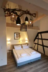 Ein gemütliches Schlafzimmer mit einem Doppelbett und modernem Holzdekor. Die Decke ist mit einem einzigartigen Beleuchtungselement geschmückt.