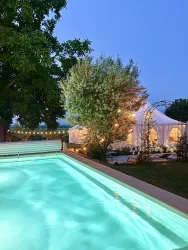 Ein einladender Pool mit glitzerndem Wasser in einer ruhigen Umgebung. Im Hintergrund steht ein Zelt unter dem Abendhimmel.