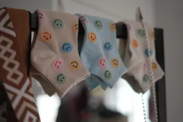 Bunte Socken mit Smiley-Motiven hängen an einer Leine. Sie sind in verschiedenen Farben und verleihen eine fröhliche Stimmung.