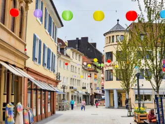 Eine belebte Einkaufsstraße mit bunten Laternen und historischen Gebäuden. Menschen schlendern entspannend durch die Fußgängerzone.