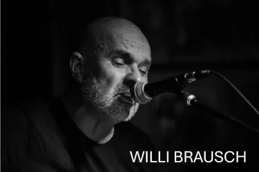 Ein Mann singt in ein Mikrofon und spielt Musik. Die Atmosphäre ist intim und musikalisch.