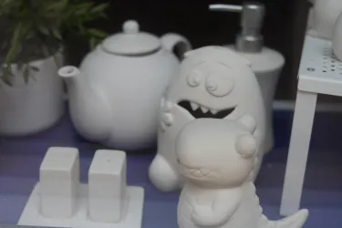 Eine Sammlung von weißen Dekorationsobjekten, darunter eine Teekanne, zwei Salz- und Pfefferstreuer sowie zwei niedliche Monsterfiguren. Die Gegenstände sind vor einem neutralen Hintergrund arrangiert.