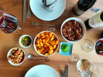 Ein festlich gedeckter Tisch mit verschiedenen Gerichten. Es gibt Gnocchi, Fleischgerichte und mehrere Weingläser.