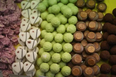 Eine Auswahl an bunten Pralinen und Süßigkeiten in verschiedenen Farben und Formen. Die Leckereien sind ordentlich nebeneinander angeordnet und wirken sehr einladend.