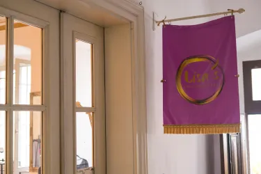 Ein lila Banner mit dem Namen "Lisa's" hängt an einer Wand. Es befindet sich in einem hellen und einladenden Raum.