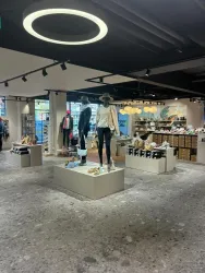 Ein modischer Einzelhandelsraum mit Kleiderständern und Schuhen. Im Vordergrund stehen Modepuppen auf Podesten.