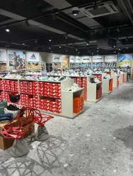 Ein modernes Sportgeschäft mit vielen Regalen voller Sportschuhe. Die Wände sind mit Markenlogos und Sportmotiven dekoriert.