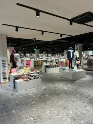 Ein modernes Schuhgeschäft mit verschiedenen Schuhen und Modeartikeln. Die Regale sind gut sortiert und das Geschäft hat eine helle, einladende Atmosphäre.