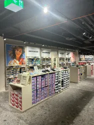 Ein modernes Schuhgeschäft mit Regalen voller Schuhkartons. An den Wänden sind Markenlogos wie Skechers und Nike zu sehen.