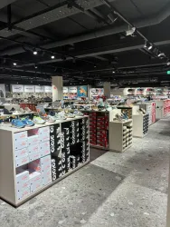 Ein großes Schuhgeschäft mit verschiedenen Regalen und Schuhen. Die Präsentation ist modern und gut beleuchtet.