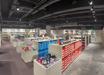 Ein gut beleuchteter Schuhladen mit vielen Regalen. Die Regale sind mit bunten Schuhen und Stiefeln in verschiedenen Größen gefüllt.