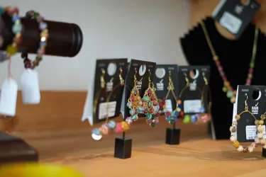 Eine schöne Auswahl an buntem Schmuck, darunter Ohrringe und Armbänder. Die Stücke sind auf Ständern präsentiert und haben ansprechende Preisschilder.