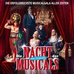 Eine bunte Bühnenaufführung mit mehreren Künstlern in fantasievollen Kostümen. Im Hintergrund sind opulente Vorhänge und Kronleuchter zu sehen.