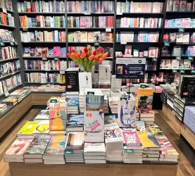 Ein schöner Buchladen mit vielen Regalen voller Bücher. In der Mitte steht ein Tisch mit aktuellen Titeln und frischen Tulpen.