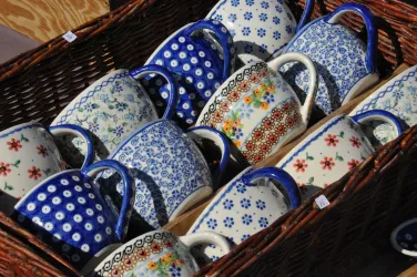 Eine Auswahl von bunten Tassen mit verschiedenen Mustern in einem Korb. Die Tassen sind hauptsächlich in Blau und Weiß gehalten.