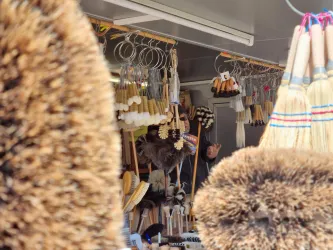 Ein Marktstand mit verschiedenen Besen und Bürsten. Im Hintergrund sind weitere Artikel zu sehen.