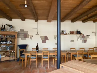 Ein gemütlicher Gastraum mit Holztischen und Stühlen. An den Wänden sind Weinfässer und dekorative Elemente angebracht.