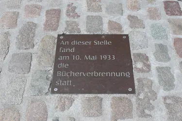Eine Gedenktafel auf einem Pflastersteinboden. Sie erinnert an die Bücherverbrennung am 10. Mai 1933.