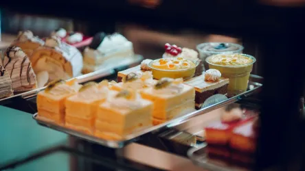 Eine Auswahl verschiedener köstlicher Desserts auf einem Tablett. Die Leckereien umfassen Kuchen, Pudding und Torten mit bunten Dekorationen.