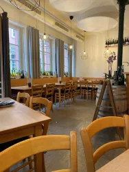 Ein gemütliches Restaurant mit Holztischen und -stühlen. Die große Fensterfront lässt viel Tageslicht herein.