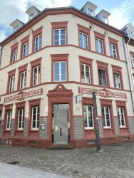 Ein historisches Gebäude mit roten und weißen Fassaden. Das Haus hat große Fenster und eine einladende Eingangstür.