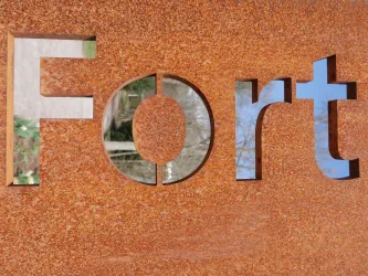 Ein metallisches Schild mit dem Wort "Fort" in großen Buchstaben. Der Hintergrund ist rostig und strukturiert.