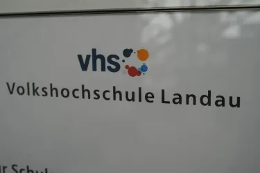 Das Bild zeigt das Logo und den Namen der Volkshochschule Landau. Es ist ein klarer und informativer Schriftzug auf einem weißen Hintergrund.