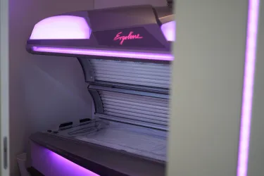 Ein Sonnenbankgerät mit lila Beleuchtung. Es steht in einem modernen Raum und ist bereit zur Nutzung.