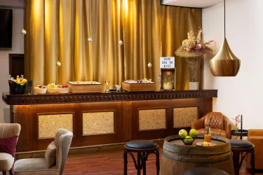 Eine elegante Bar mit einer goldenen Vorhangdekoration. Auf der Theke sind Getränke und Snacks angerichtet.