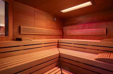 Eine moderne Sauna mit Holzverkleidung und gemütlichen Bänken. Sanftes, farbiges Licht schafft eine entspannende Atmosphäre.