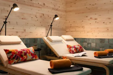 Ein entspannender Ruheraum mit modernen Liegen und bunten Kissen. Sanfte Beleuchtung sorgt für eine gemütliche Atmosphäre.