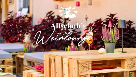 Eine gemütliche Weinlounge mit Holzmöbeln und bunten Pflanzen. Auf den Tischen stehen dekorative Blumen und ein Getränk.