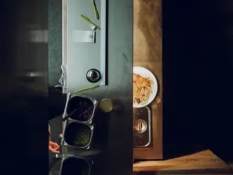 Eine Küchenzeile mit verschiedenen Schalen für Zutaten und einem Teller mit einer Mahlzeit. Die Arbeitsfläche ist aus Edelstahl und gut beleuchtet.