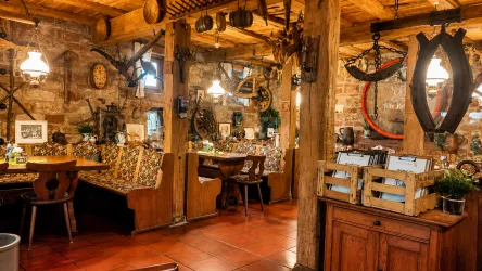 Ein gemütliches Restaurant mit rustikalem Holzdekor und traditionellen Elementen. Tische und Bänke laden zum Verweilen ein.