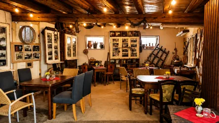 Ein gemütliches Café mit holzigem Interieur und warmem Licht. An den Wänden hängen nostalgische Fotografien und es stehen Tische mit Blumenvasen.