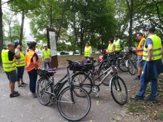 Eine Gruppe von Radfahrern in gelben Warnwesten steht zusammen und diskutiert. Um sie herum sind mehrere Fahrräder abgestellt.