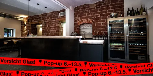 Eine moderne Bar mit Holz- und Steinwänden. Im Hintergrund sind Weinschränke und eine Anrichte zu sehen.