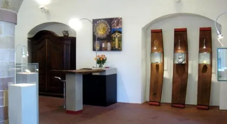 Ein eleganter Ausstellungsraum mit Holzregalen und einem Empfangstresen. An den Wänden hängen Kunstwerke, und es gibt eine Blumenvase auf dem Tisch.